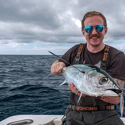 Josh Phillips of Washington's Evergreen Coast holding an albacore tuna on the deck of a fishing boat offshore