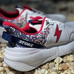Stoke FO-MO 2Fiddy wide sneakers in red, white, and blue resting on gravel